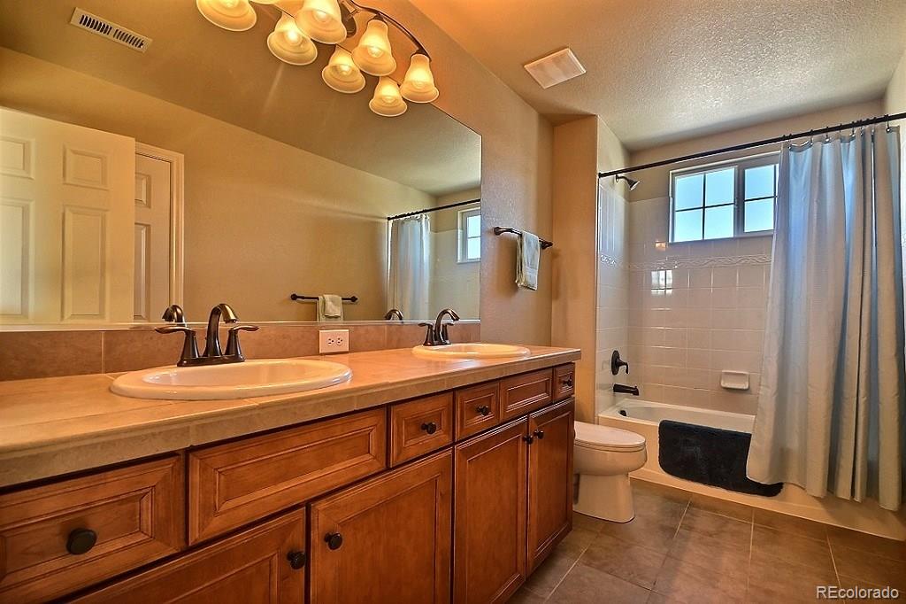 17874 West 77th Lane Arvada, CO 80007 - Photo 29 of 33 a spacious bathroom with a double vanity sink a large mirror and a bathtub