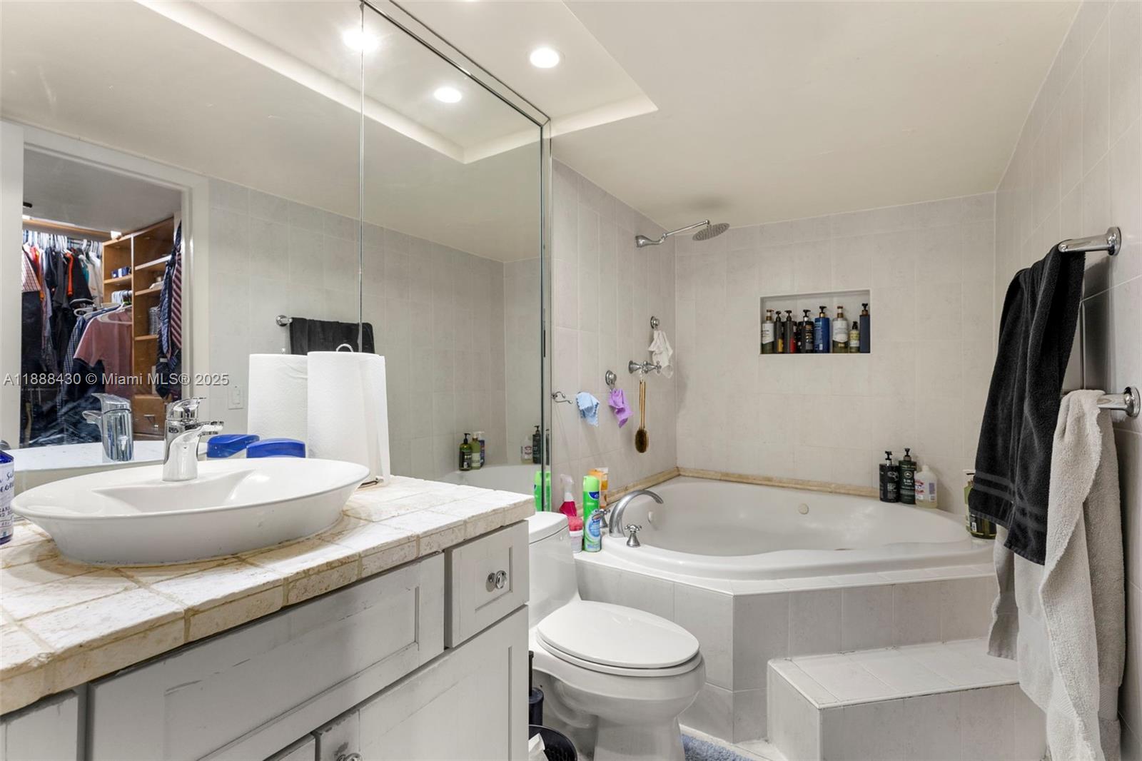 19440 Northeast 26th Avenue, Unit 53B Miami, FL 33180 - Photo 24 of 33 a bathroom with a sink a toilet and a mirror