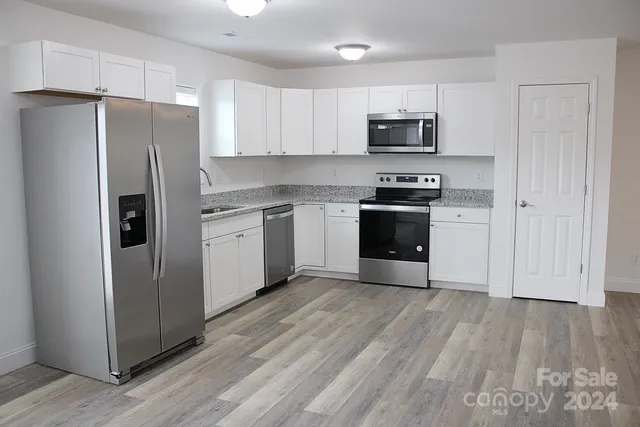 a kitchen with granite countertop a refrigerator and a stove top oven