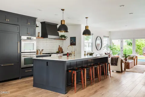 a kitchen with stainless steel appliances kitchen island granite countertop a sink a stove and a wooden floors