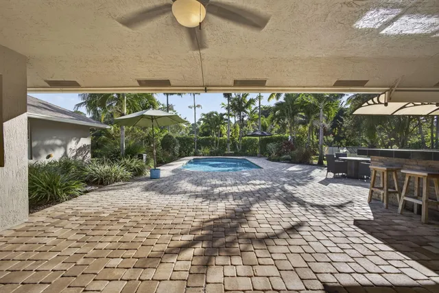 a view of a patio with table and chairs potted plants and palm trees