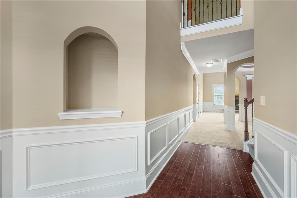12 Juno Street Fort Mitchell, AL 36856 - Photo 29 of 43 Corridor featuring a wainscoted wall, arched walkways, a decorative wall, dark wood-style flooring, and ornamental molding
