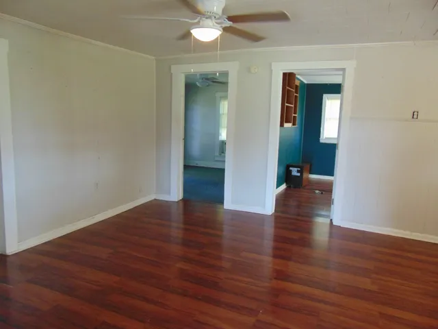 an empty room with wooden floor and a ceiling fan