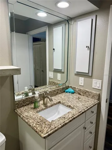 a bathroom with a granite countertop sink and a mirror
