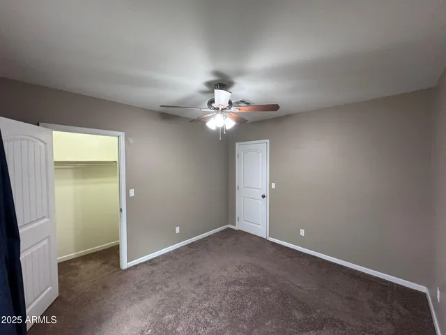 an empty room with closet and a ceiling fan
