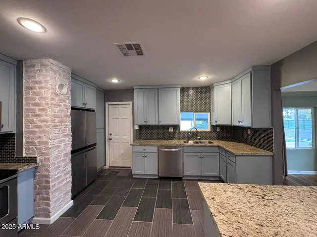 a kitchen with granite countertop a refrigerator and a stove top oven