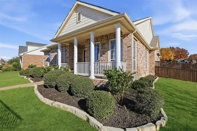 a view of a house with brick walls and a yard with plants