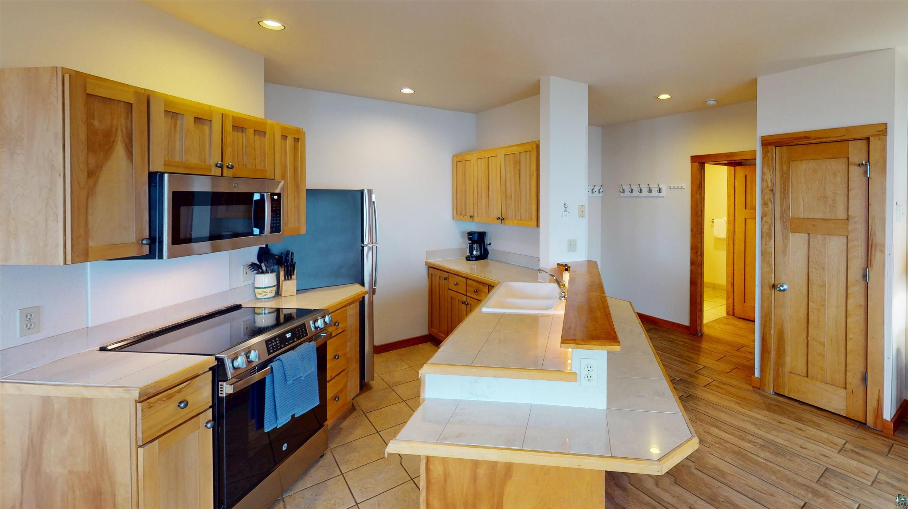 504-506 Poplar River Road, Unit 505 Lutsen, MN 55612 - Photo 9 of 39 Kitchen featuring light wood cabinetry, stainless steel appliances, tile countertops, and a breakfast bar