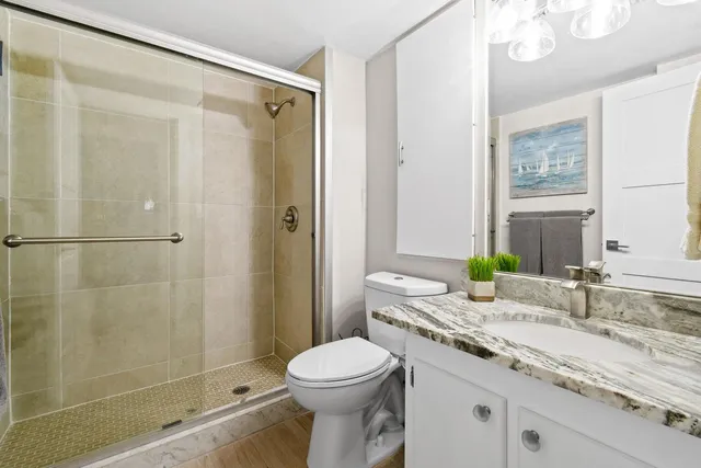 a bathroom with a granite countertop sink toilet and shower