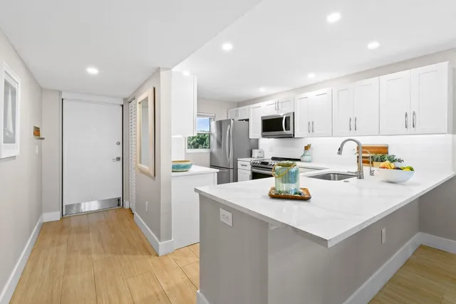 a kitchen that has a lot of white cabinets and stainless steel appliances
