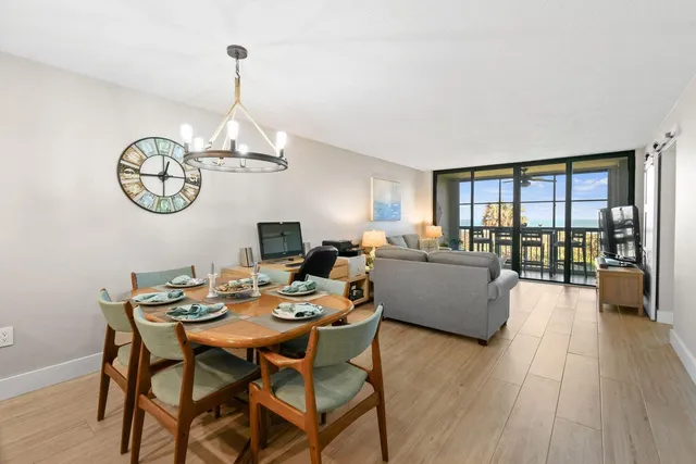 a dining room with wooden floor a chandelier a wooden table and chairs