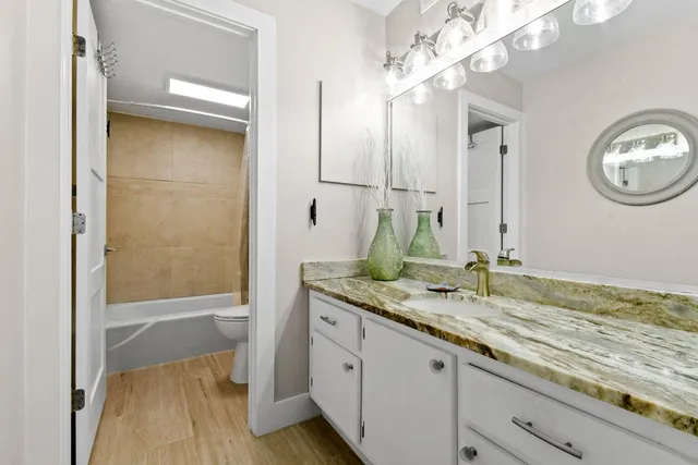 a bathroom with a granite countertop sink a mirror and a bathtub