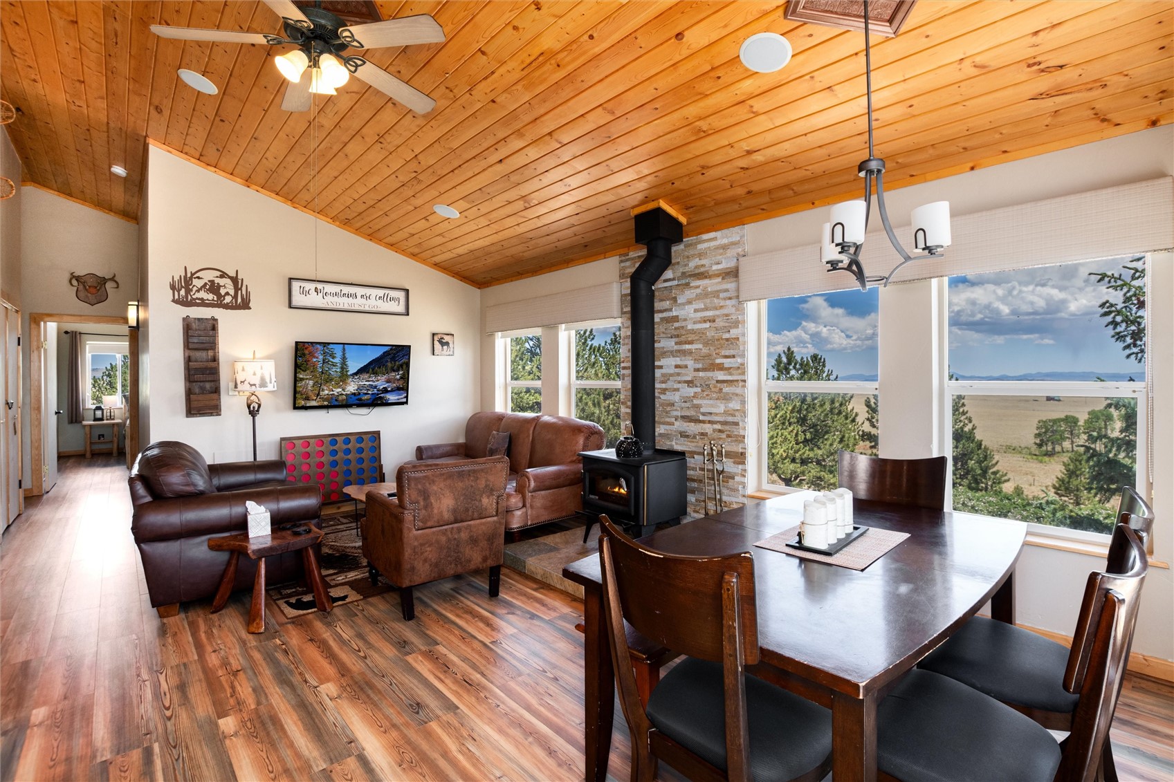 1301 Sheep Ridge Road Fairplay, CO 80440 - Photo 12 of 49 Vaulted wood-paneled ceilings, wood-finish flooring, and a stone-clad wood-burning stove define this open-concept living and dining area