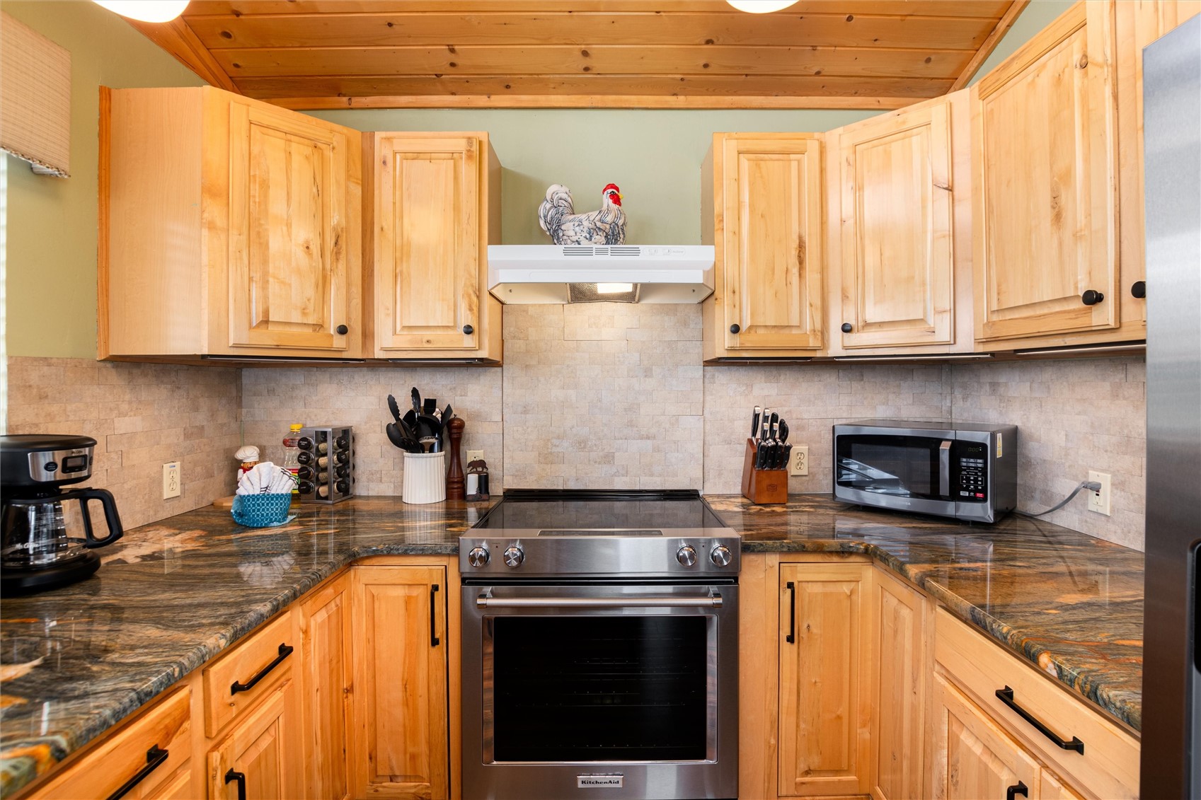 1301 Sheep Ridge Road Fairplay, CO 80440 - Photo 18 of 49 U-shaped kitchen with wood cabinetry, dark countertops, a tile backsplash, and a stainless steel range