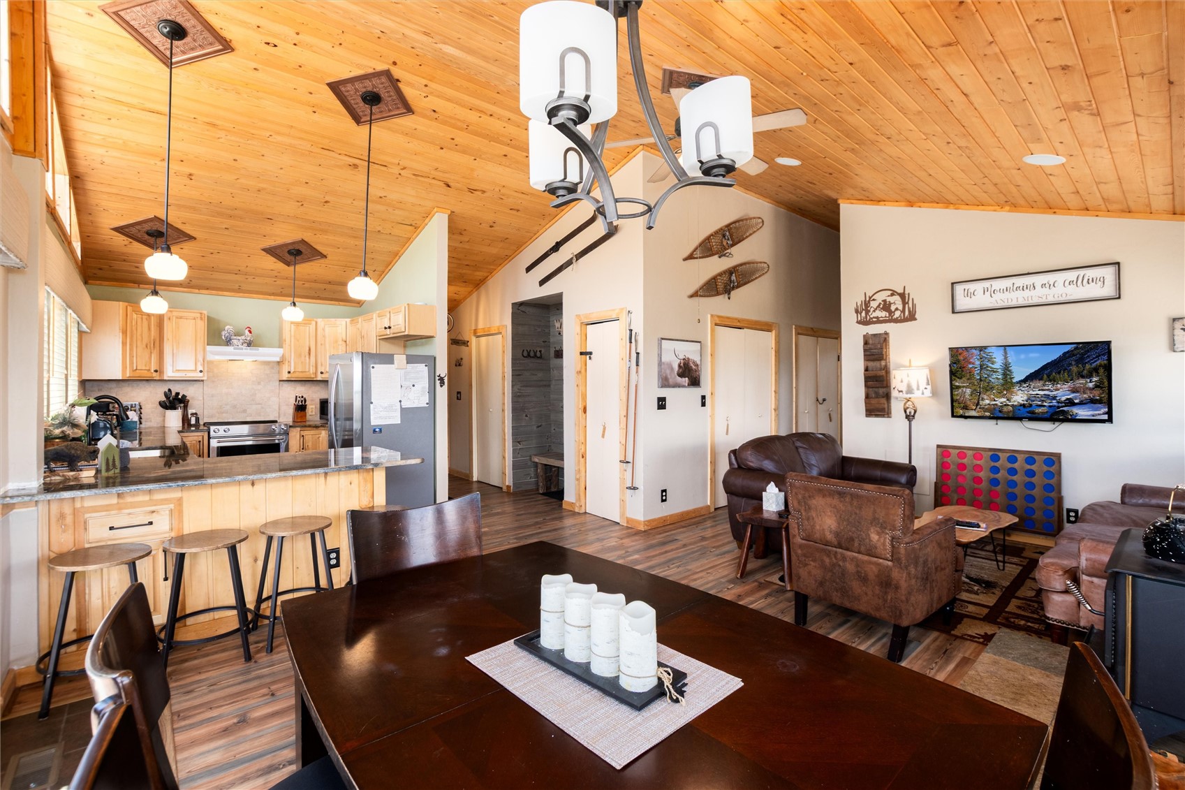 1301 Sheep Ridge Road Fairplay, CO 80440 - Photo 2 of 49 Open-concept living space with vaulted wood-plank ceiling, wood-finish flooring, and a kitchen featuring light wood cabinetry, stainless steel appliances, and a breakfast bar with pendant lighting