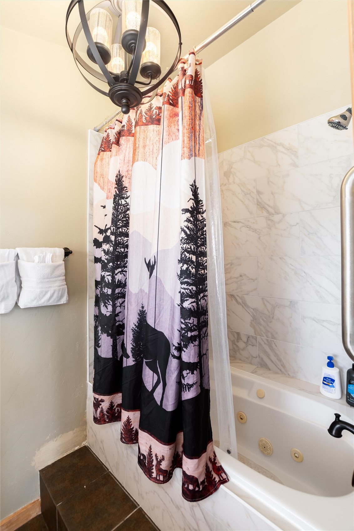 1301 Sheep Ridge Road Fairplay, CO 80440 - Photo 37 of 49 Jetted soaking tub with a white finish, complemented by marble-finish wall tiling and a dark bronze orb chandelier