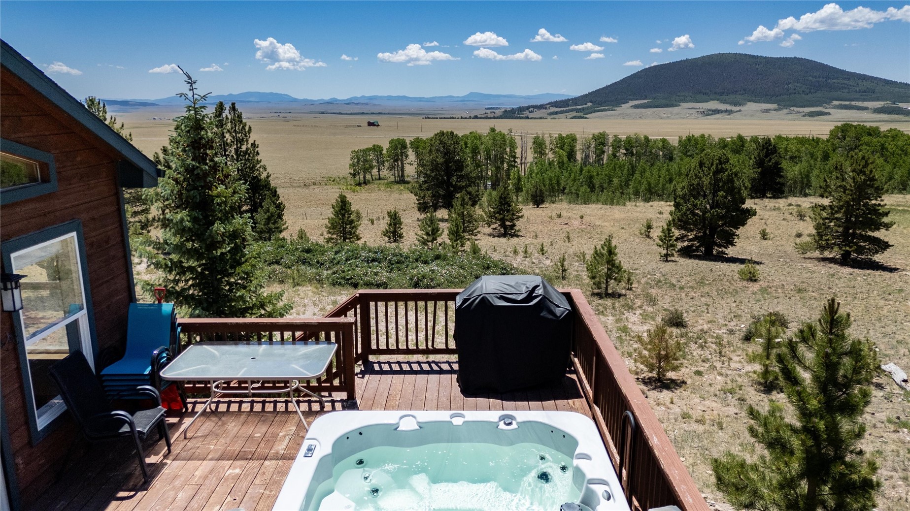 1301 Sheep Ridge Road Fairplay, CO 80440 - Photo 41 of 49 Wood-sided exterior with a spacious wood deck, featuring an integrated hot tub and panoramic high-desert scenery with distant mountains