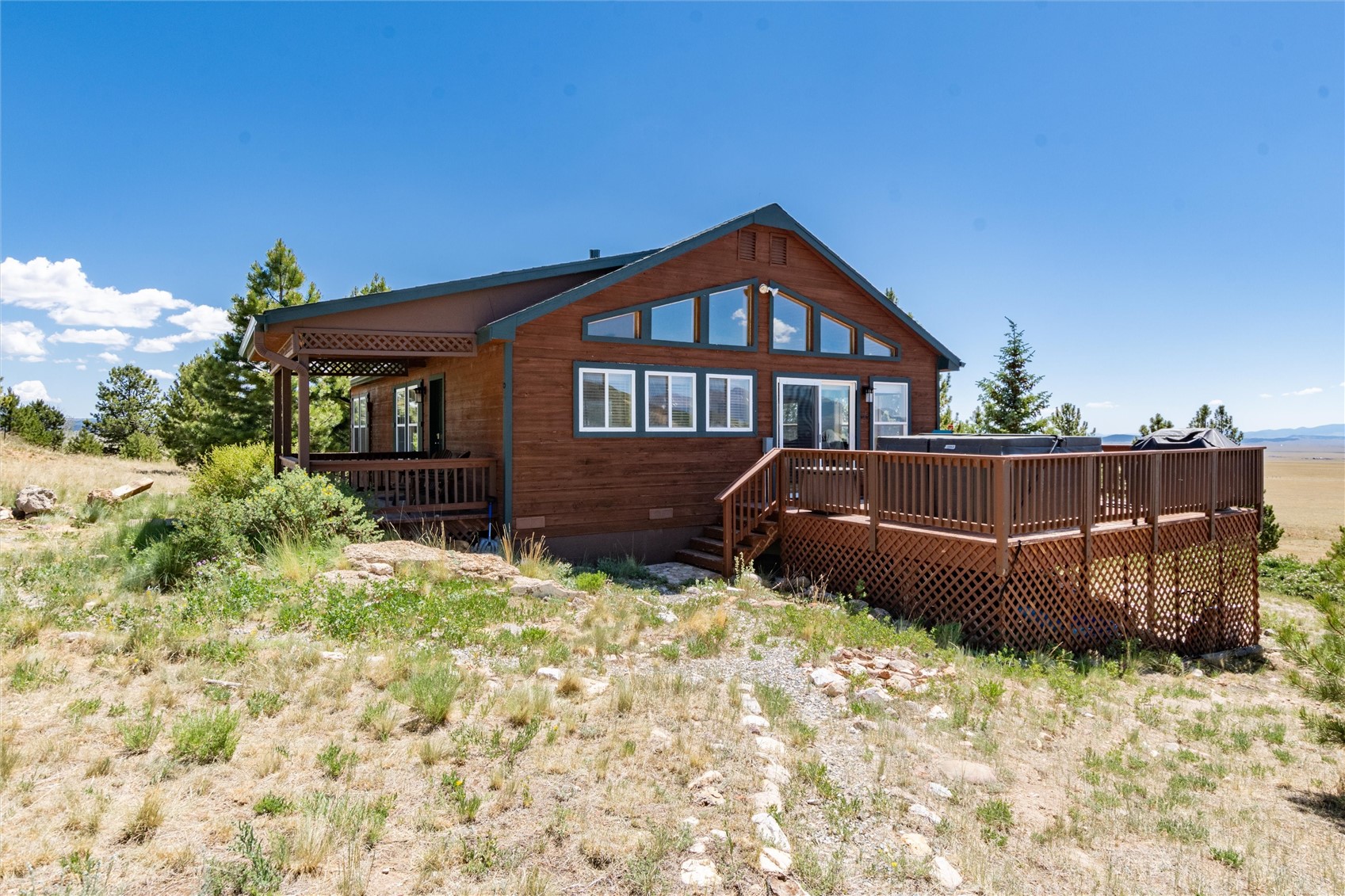 1301 Sheep Ridge Road Fairplay, CO 80440 - Photo 46 of 49 Wood-sided home with a dark roofline, featuring a spacious exterior deck, a covered porch, and extensive window placements