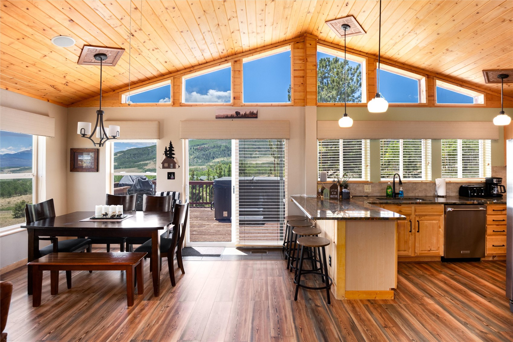 1301 Sheep Ridge Road Fairplay, CO 80440 - Photo 7 of 49 Spacious open-concept living area featuring a vaulted wood-plank ceiling, wood-finish flooring, a contemporary dining area, and a kitchen with stainless steel appliances and a breakfast bar