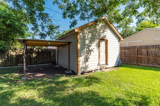 a view of backyard with small cabin and wooden fence