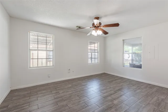 a view of an empty room with wooden floor and a window
