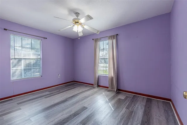 a view of an empty room with a window and wooden floor