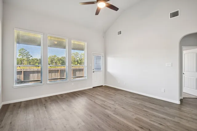 an empty room with wooden floor and windows