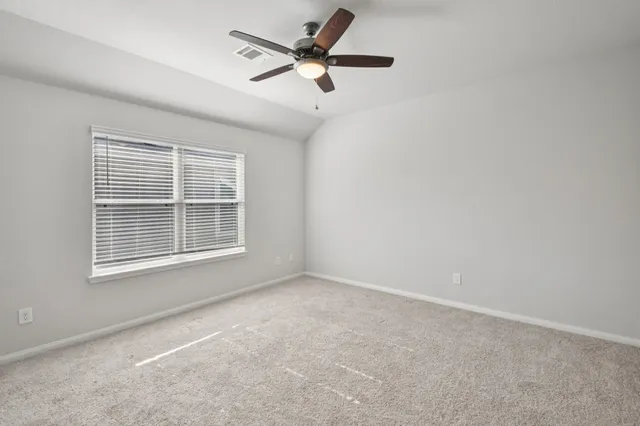 an empty room with window and ceiling fan