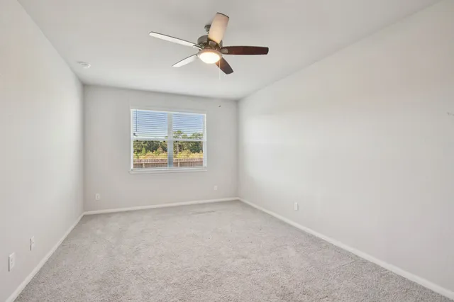 an empty room with window and ceiling fan