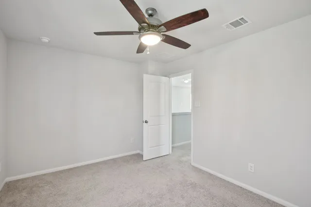 an empty room with a ceiling fan and carpet