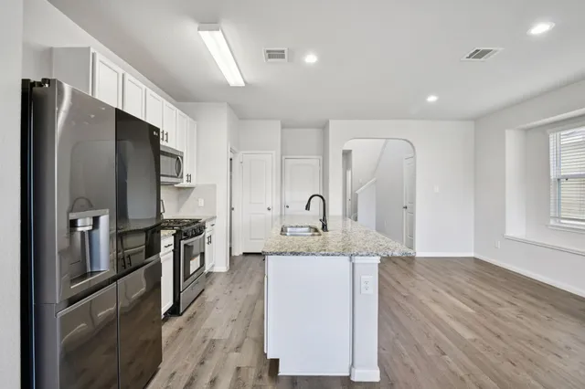 a kitchen with stainless steel appliances granite countertop a refrigerator a sink a stove and oven