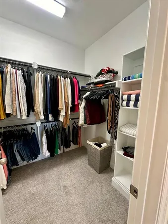 a view of walk in closet with clothes and shoes
