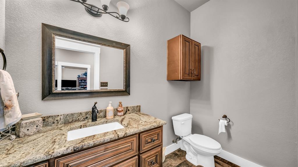 143 Oak Tree Drive Poolville, TX 76487 - Photo 23 of 40 a bathroom with a granite countertop toilet sink and mirror