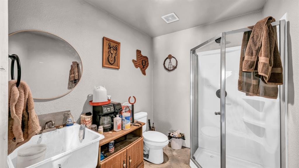 143 Oak Tree Drive Poolville, TX 76487 - Photo 35 of 40 a bathroom with a sink mirror toilet and shower