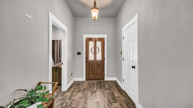 a view of a hallway with wooden floor and a chandelier