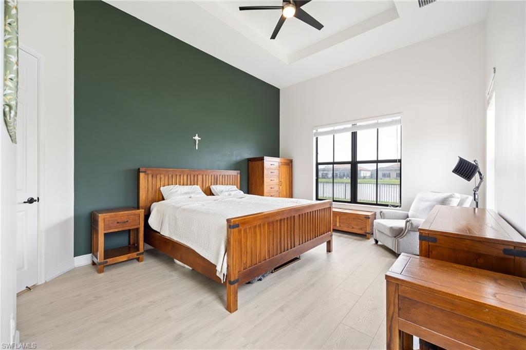 5116 Salerno Street Ave Maria, FL 34142 - Photo 18 of 36 Bedroom with light wood-style floors, a ceiling fan, and a tray ceiling
