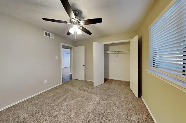 an empty room with closet and a chandelier fan