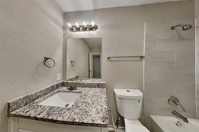 a bathroom with a granite countertop sink a toilet and a mirror