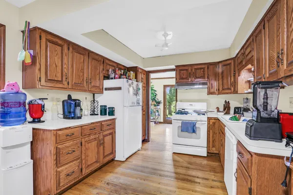 a kitchen with a refrigerator a stove top oven a sink dishwasher and wooden cabinets with wooden floor