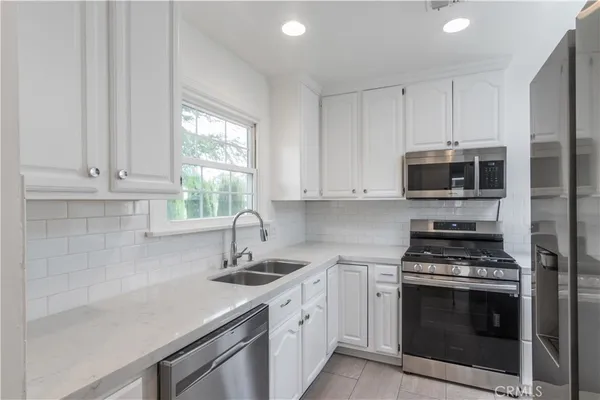a kitchen with cabinets stainless steel appliances a sink and a window