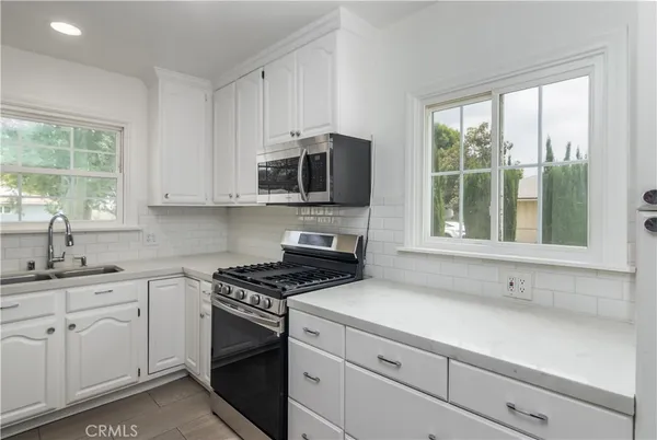 a kitchen with cabinets appliances a sink and a window