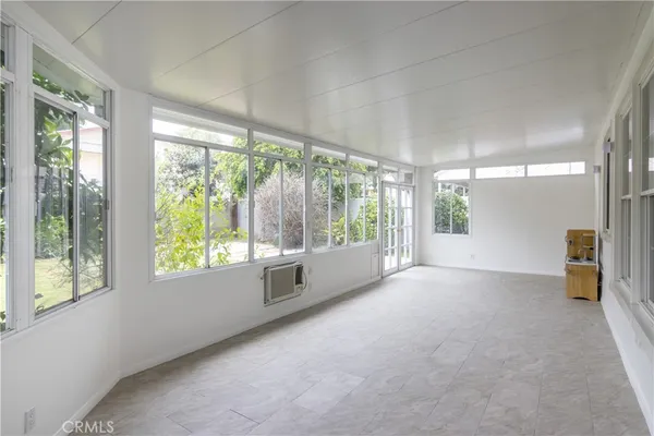 a view of an empty room with window and a kitchen