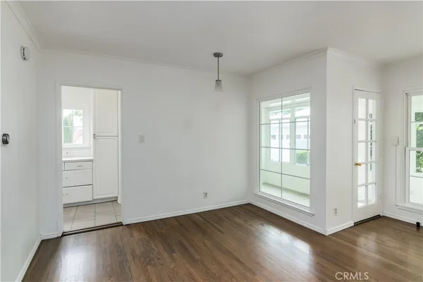 an empty room with wooden floor cabinet and windows