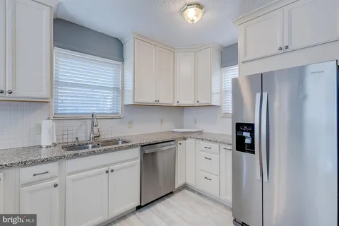 a kitchen with white cabinets and refrigerator