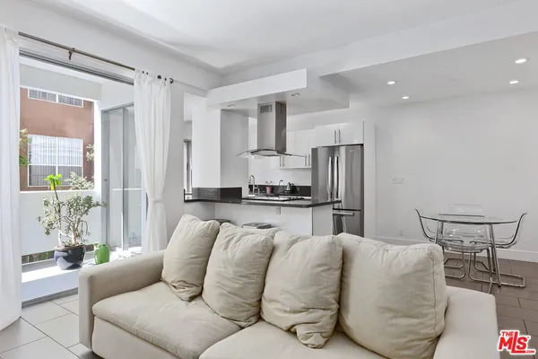a living room with stainless steel appliances furniture a refrigerator and kitchen island