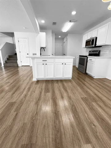 a large kitchen with stainless steel appliances granite countertop a lot of cabinets and wooden floor