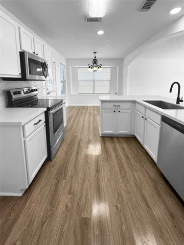 a kitchen with wooden floors a sink stainless steel appliances and cabinets