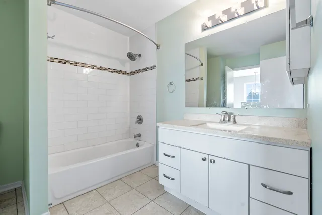 a bathroom with a granite countertop sink a mirror a bathtub and shower