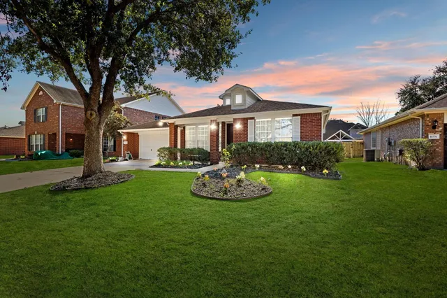 a front view of a house with a garden and trees