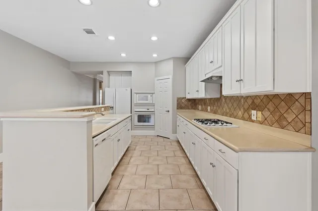 a kitchen with white cabinets sink and white appliances